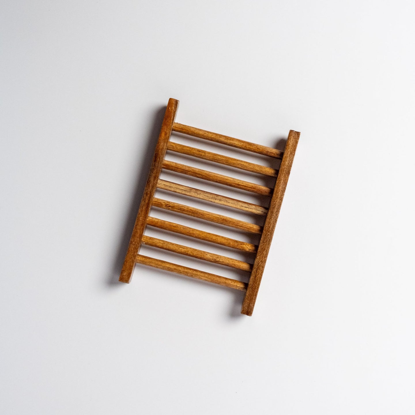 A brown bamboo ladder style soap dish on a white background.