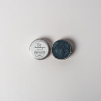 An open aluminum tin of midnight blue powder on a white background with a white label that says Lakota Made BHanchokanyan Dark Blue Eyeshadow Ingredients mica powder, kaolin clay powder, arrowroot powder.