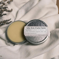 Close up of a metal tin full of beeswax skin balm with a white label that says Abla Kela Calm Balm