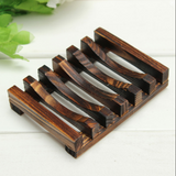 A dark brown bamboo soap dish on a white background with green leaves